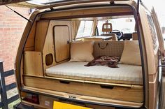 the back end of a van with a bed and pillows in it's cargo area