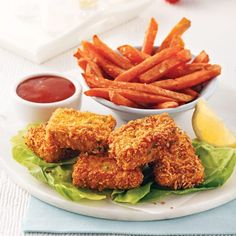 fried chicken and french fries on a plate with ketchup, lemon wedges and dipping sauce