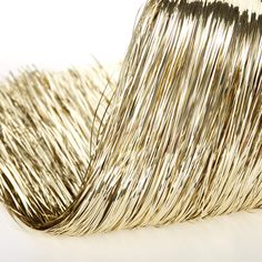 a roll of metallic foil on a white surface with some gold tinsel in the background