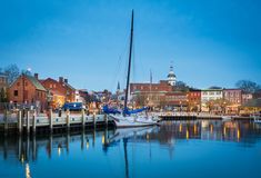 a sailboat is docked in the harbor at night with other boats and buildings around it