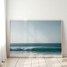 an empty room with a painting on the wall next to a wooden floor and white curtains