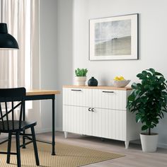 a dining room with a table and chairs next to a potted plant in the corner