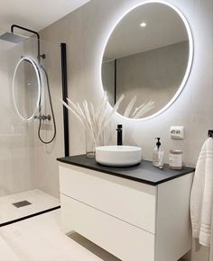 a bathroom with a round mirror above the sink and a black counter top under it