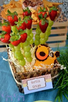 a basket filled with grapes and strawberries on top of a table