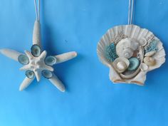 two seashells and starfish hanging from chains on a blue background with sea shells