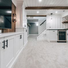 an empty kitchen with white cabinets and wood beams on the ceiling is pictured in this image