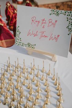 a table topped with lots of gold bells and a sign that says row the ball wish them well