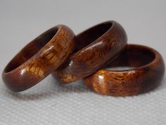 three wooden rings sitting next to each other on top of a white tableclothed surface