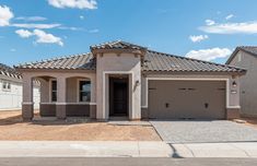 a house with two garages in front of it and a blue sky behind it