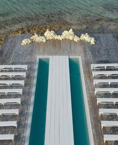 an aerial view of chairs and tables on the water's edge, with white flowers in the foreground