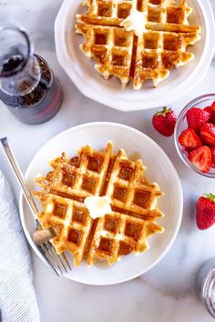 two plates with waffles and strawberries on them