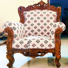 an ornate wooden chair with white and red upholstered fabric on the armrests