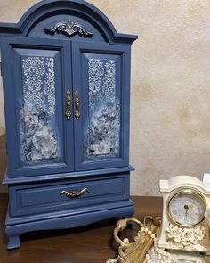 a blue armoire sitting on top of a table next to a clock and key