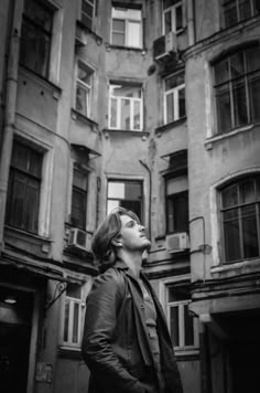 a man standing in front of an old building looking up into the sky with his eyes closed