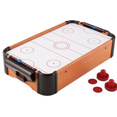 an air hockey table with two red pucks and three plastic cups next to it