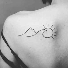 the back of a woman's shoulder with a sun and mountains tattoo on it