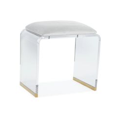 an acrylic stool with gold trimmings and a white cushion on top