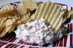 a red and white plate topped with chips and coleslaw cheese salad next to potato chips