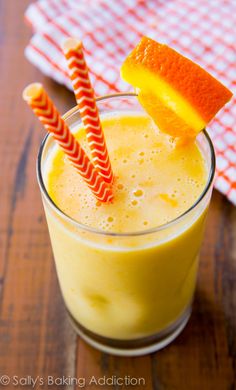 a glass filled with orange juice and two straws sticking out of the top of it