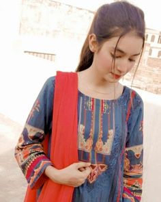 a young woman is looking down at her cell phone while wearing a blue and red outfit