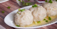 three dumplings are sitting on a plate with sauce and scallion garnishes