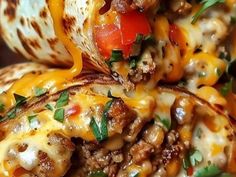 several burritos stacked on top of each other with cheese, meat and vegetables