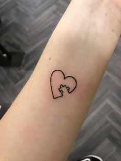 a small tattoo on the arm of a woman with two pieces in the shape of a heart