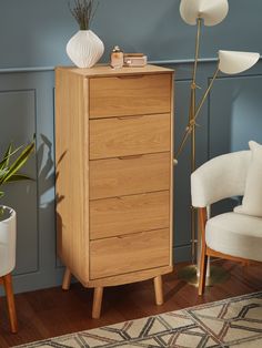 a wooden chest of drawers sitting next to a white chair