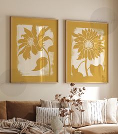 two sunflowers are hanging on the wall above a couch in a living room