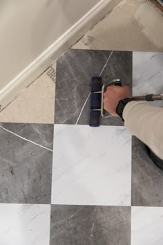 a person is using a tool to clean the tile on the floor with a roller