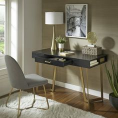 a desk with a lamp, chair and pictures on the wall in front of it