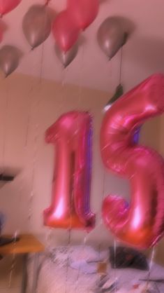 some balloons are hanging from the ceiling in front of a room with a bed and table