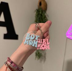 a person holding a keychain with the words boy, girl, and mom written on it