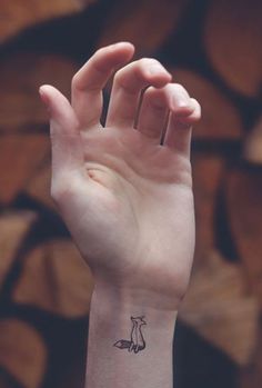 a hand with a small fox tattoo on it's left wrist and the word foxes written in black ink