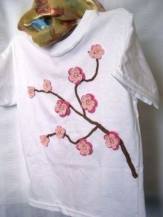 a white t - shirt with pink flowers on it and a scarf hanging from the neck