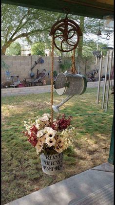 a bucket filled with flowers sitting on top of a grass covered field next to a tree