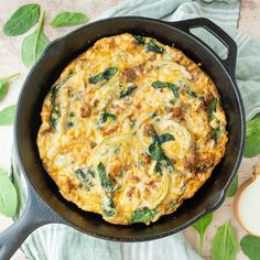 an omelet with spinach and cheese in a skillet on a table