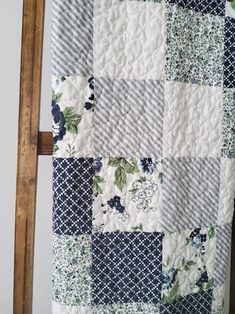 a blue and white patchwork quilt hanging on a wooden ladder next to a wall