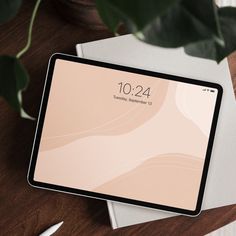 an ipad sitting on top of a wooden table next to a pen and laptop computer