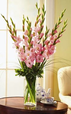 a vase filled with pink flowers sitting on top of a table next to a window