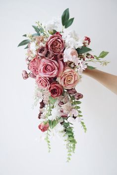 a bride's bouquet with pink and white flowers is being held by her hand