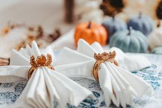 two napkins with rings on them sitting on a table in front of pumpkins