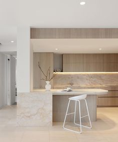 a modern kitchen with marble counter tops and white stools