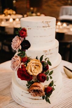 a three tiered cake with flowers on it sitting on top of a wooden table