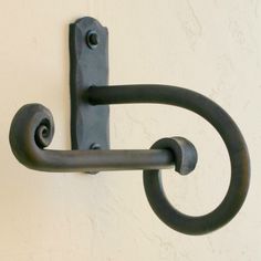 a metal hook on the side of a white wall with a black handle and loop