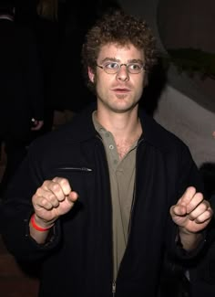 a man with glasses pointing his finger at the camera