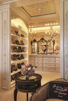 a room filled with lots of shoes and chandelier above a table in front of a mirror