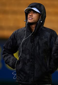 a man wearing headphones standing in front of a wooden wall with his hands on his hips