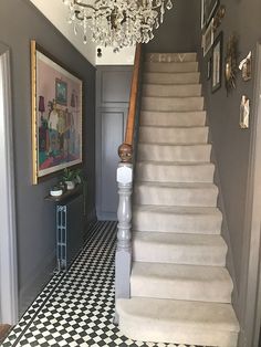 a staircase with chandelier and black and white checkered flooring in a house