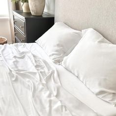 a bed with white sheets and pillows in a room